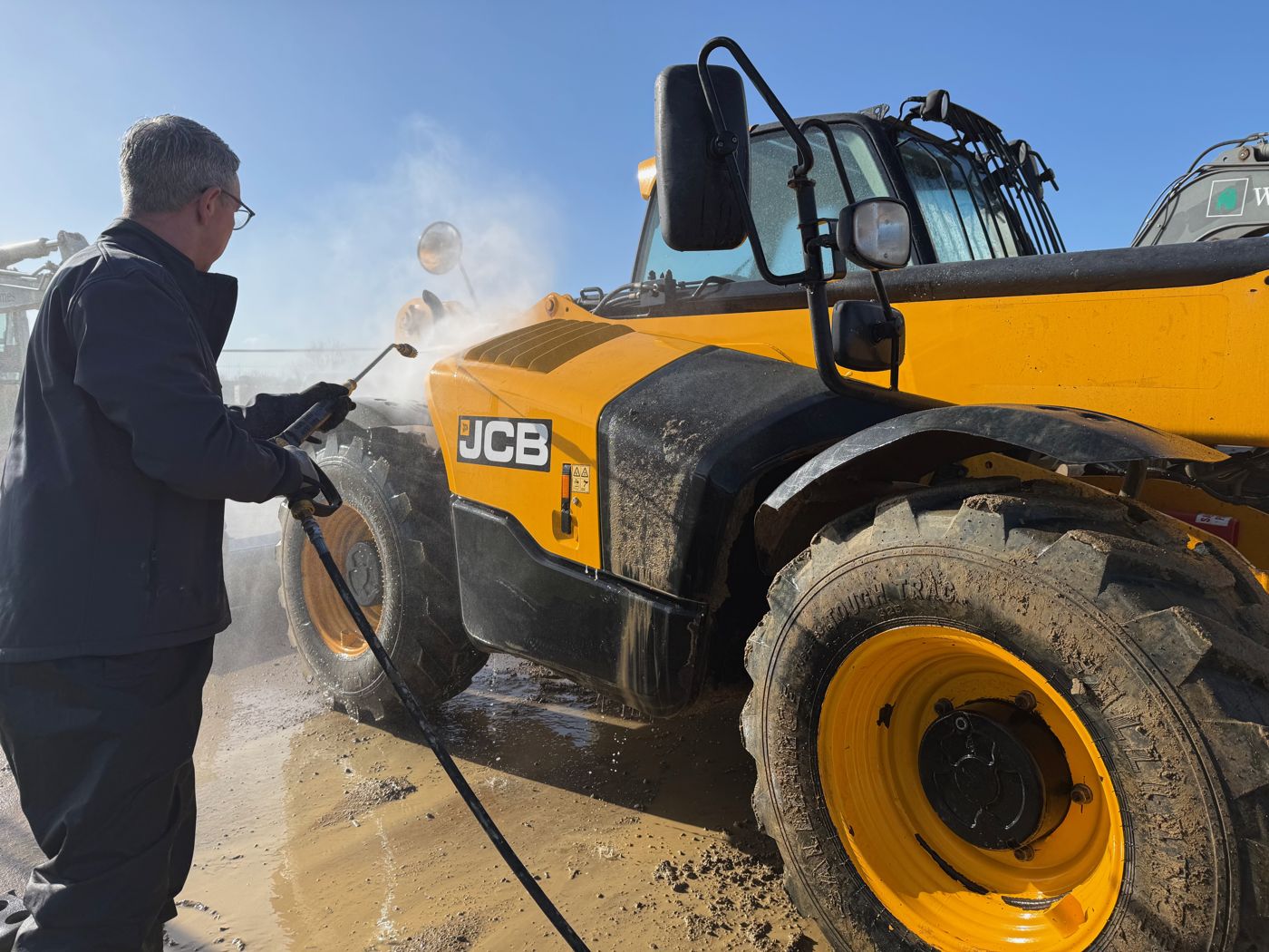 JCB telehandler being pressure washed by Fenland Property Care